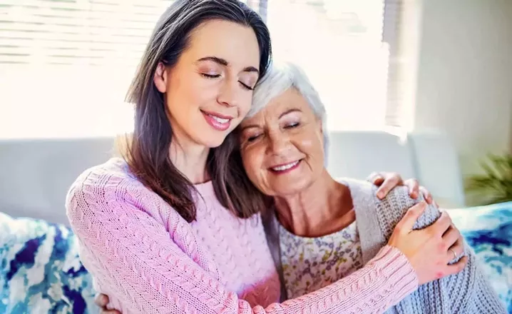 A women smiles and hugs her elderly mother. A women smiles and hugs her elderly mother.