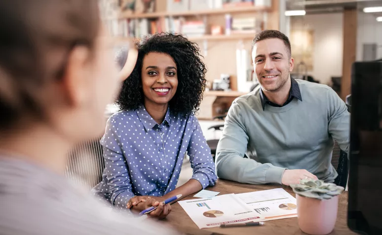 A young couple listens to their Edward Jones financial advisor during a meeting at a cafe. A young couple listens to their Edward Jones financial advisor during a meeting at a cafe.