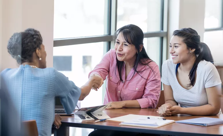 Women shaking hands across a table Women shaking hands across a table