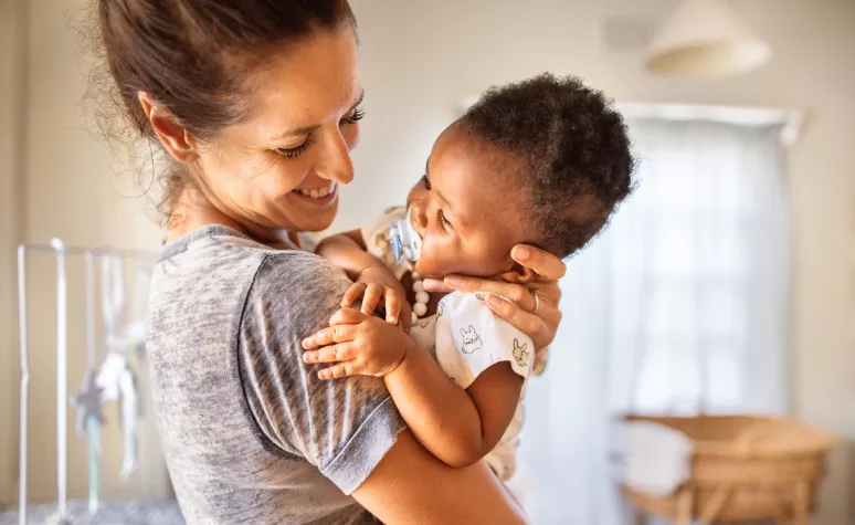 A single mom holding her young child and smiling A single mom holding her young child and smiling