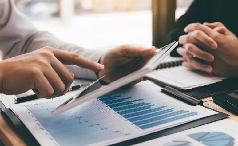 An Edward Jones financial advisor shares stock market information with a client on documents and a tablet. An Edward Jones financial advisor shares stock market information with a client on documents and a tablet.